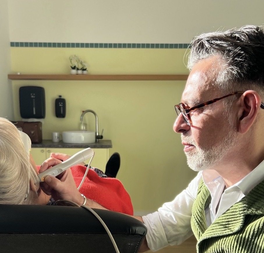 Walter Argentino applique le laser doux sur l'oreille d'une cliente installée dans le fauteuil du cabinet